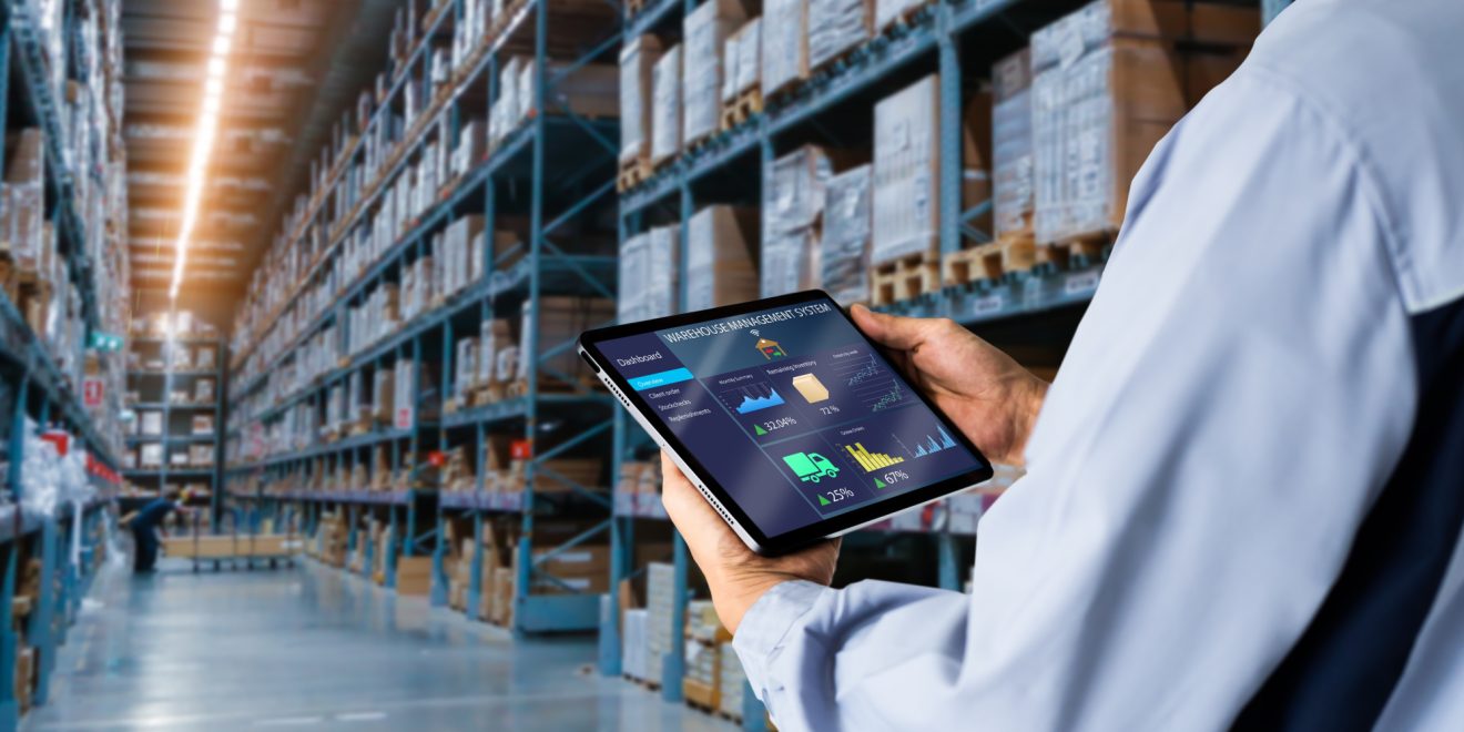 A person in a warehouse checks their tablet