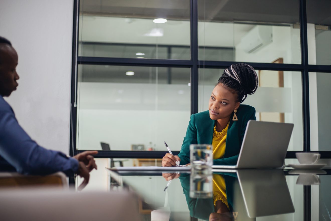 Two people discuss a project in an office meeting room