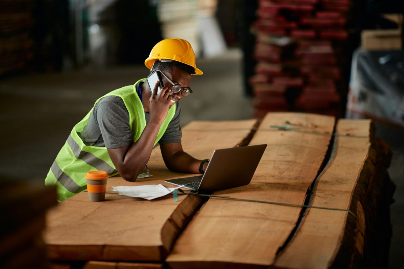 A person on a job site on a laptop talks on the phone