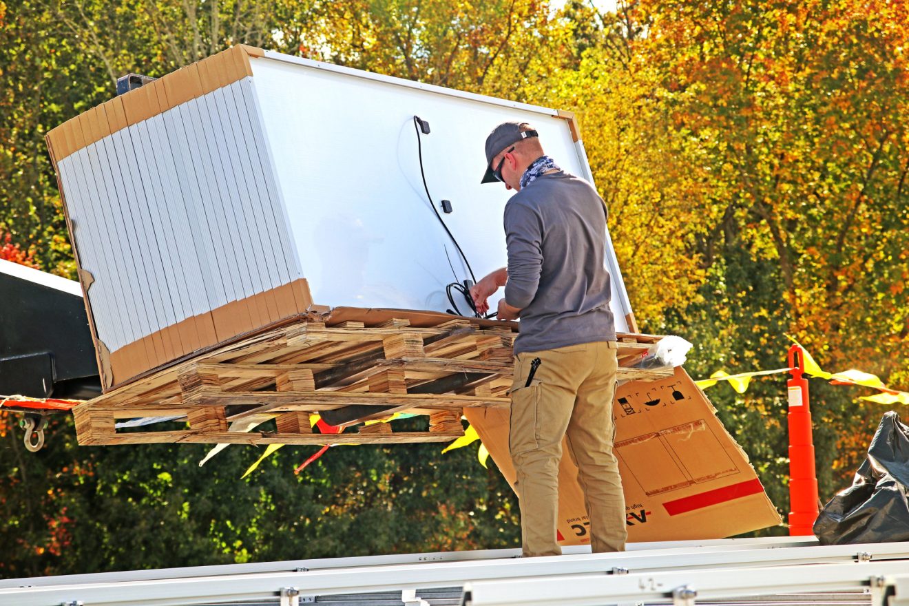 A crate of solar panels being inspected by a worker.