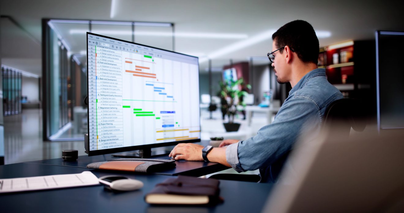 Man using a computer to update a project Gantt chart
