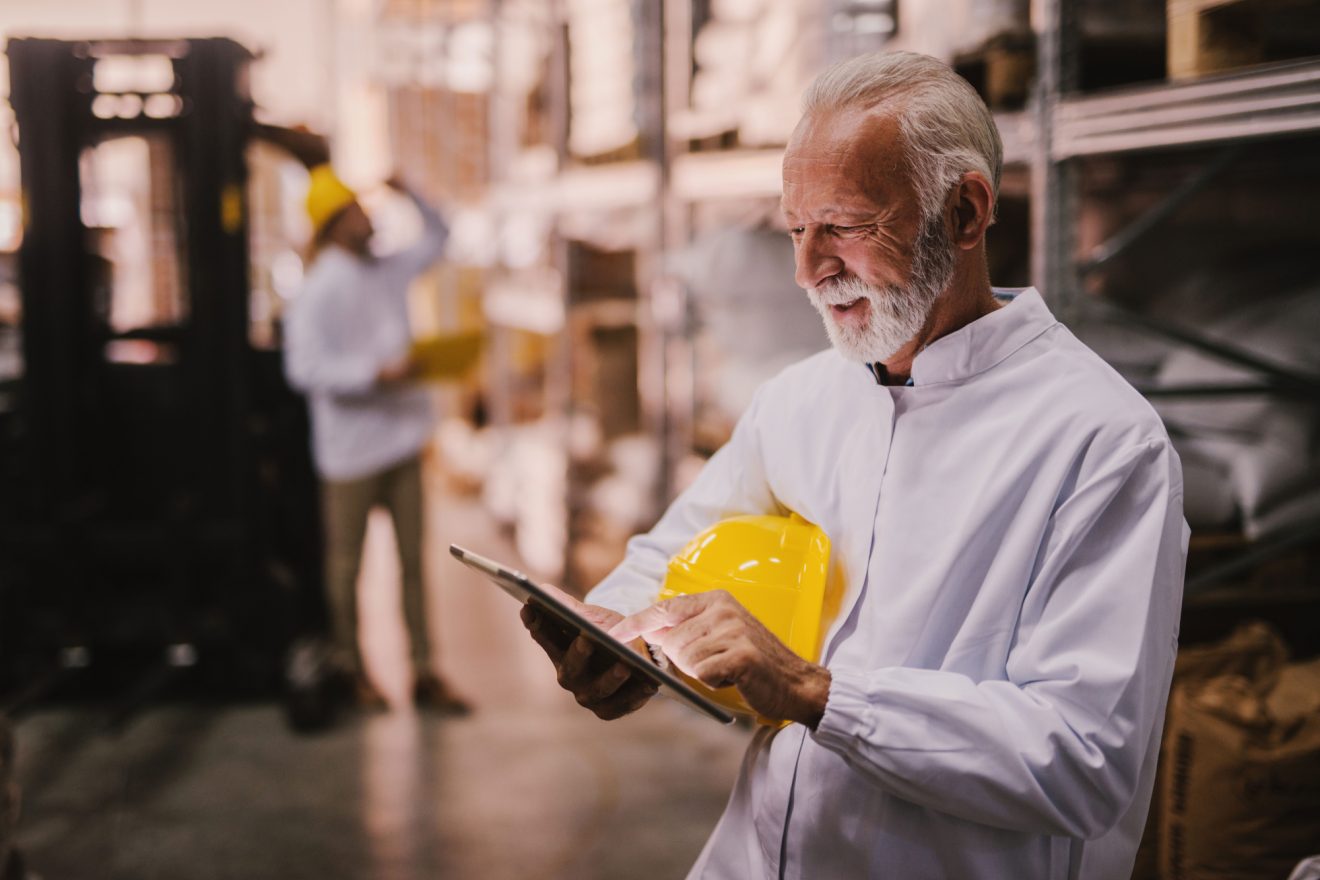Man holding a hard hat looking at a tablet