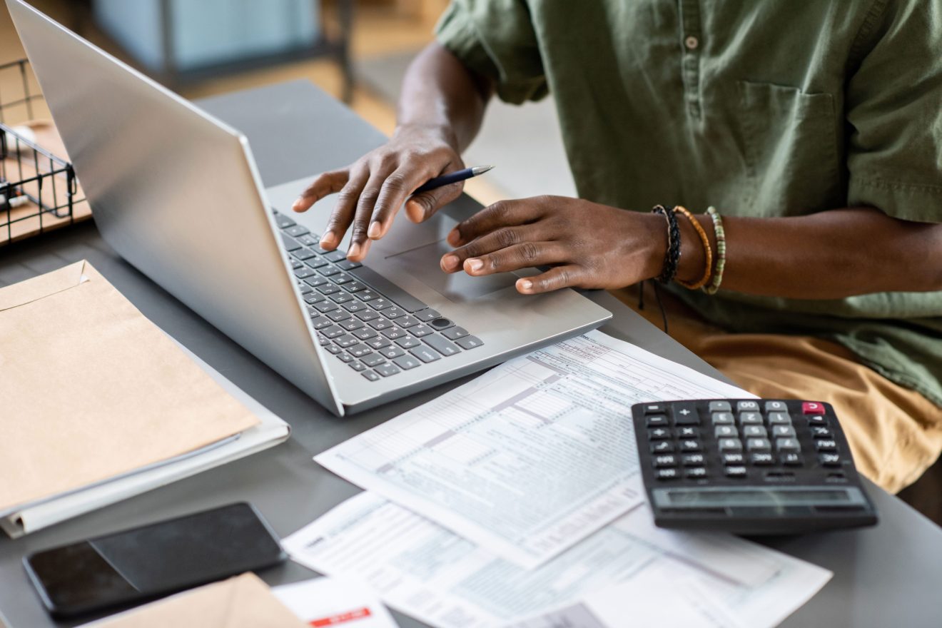 Man working on laptop with calculator