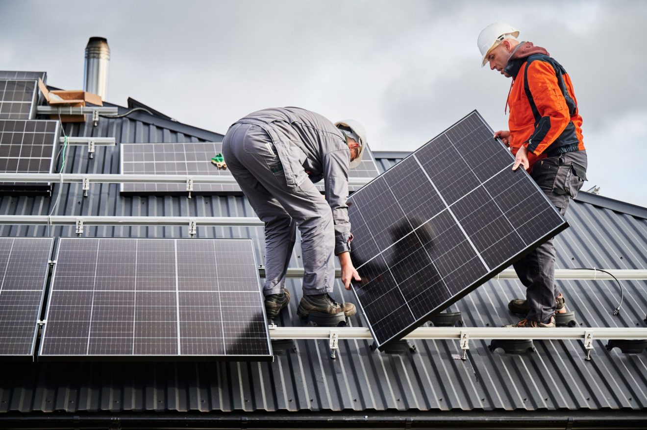 Two people work together to deliver and install solar panels