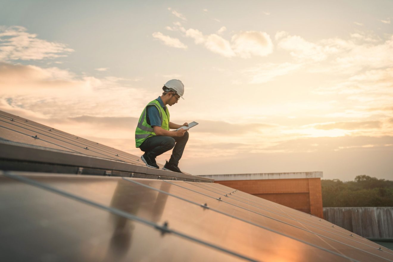 A person checks Quickbase while inspecting a solar panel