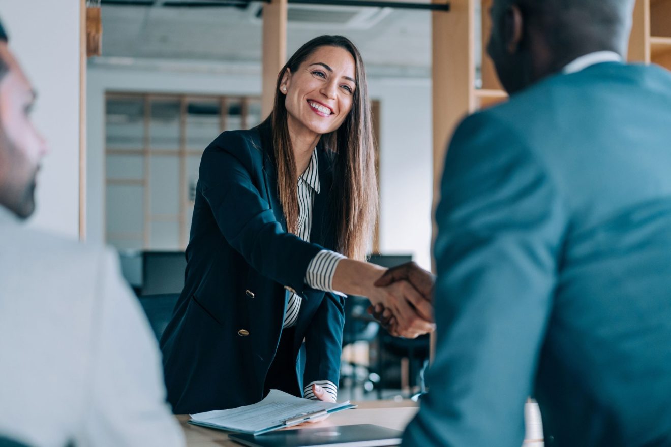 Two people shake hands in a meeting
