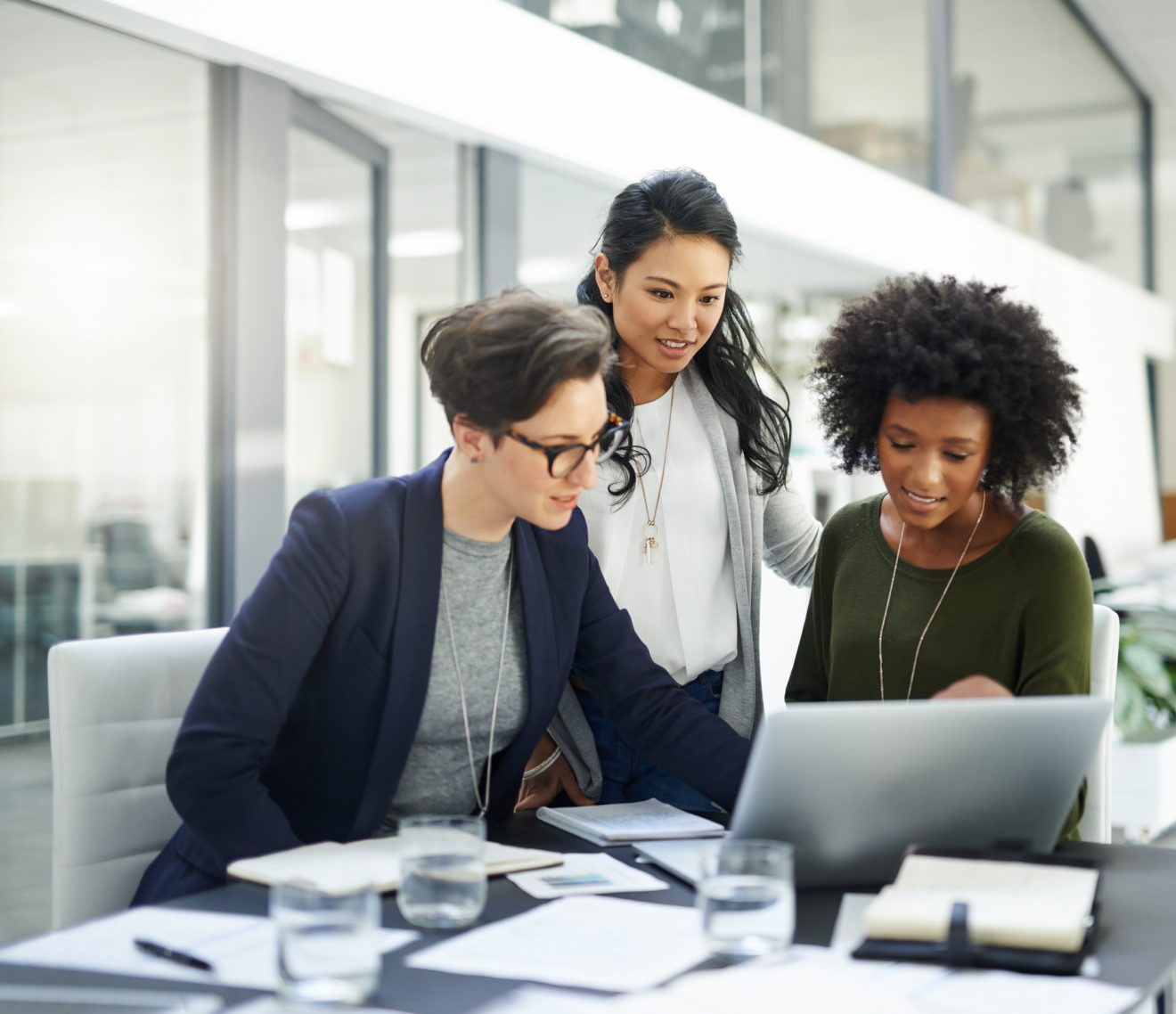 A project manager leads a discussion around a laptop