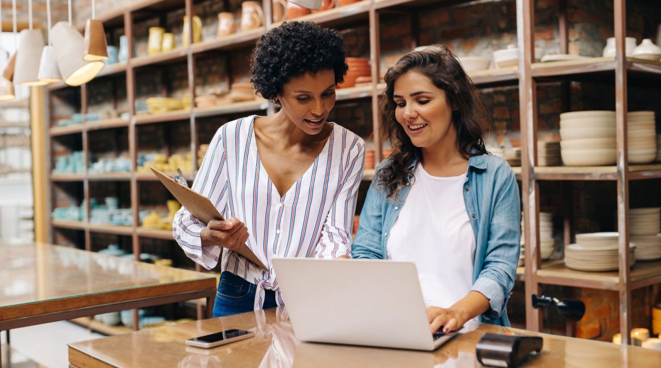 Two people work together on a laptop in the back room of their retail store