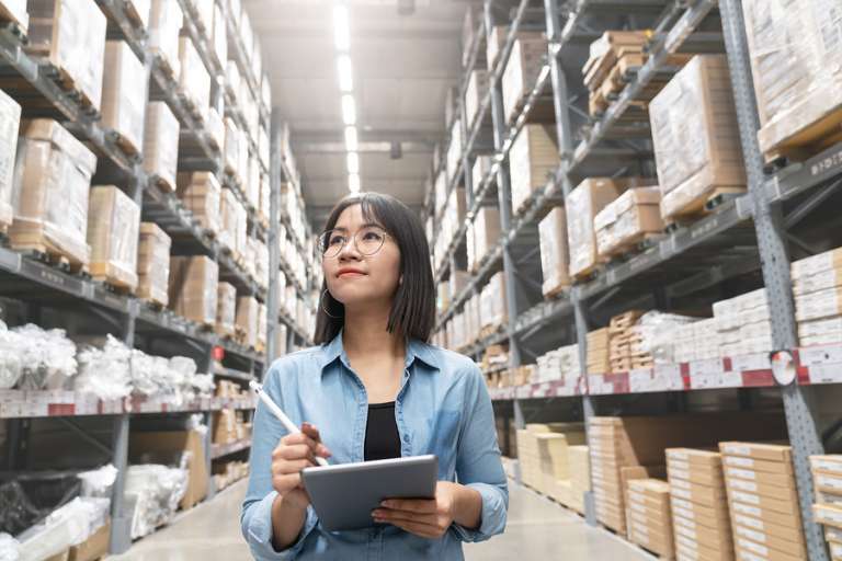 Supply chain woman in warehouse on tablet
