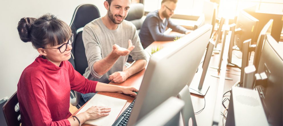woman and man looking at large computer monitor discussing something