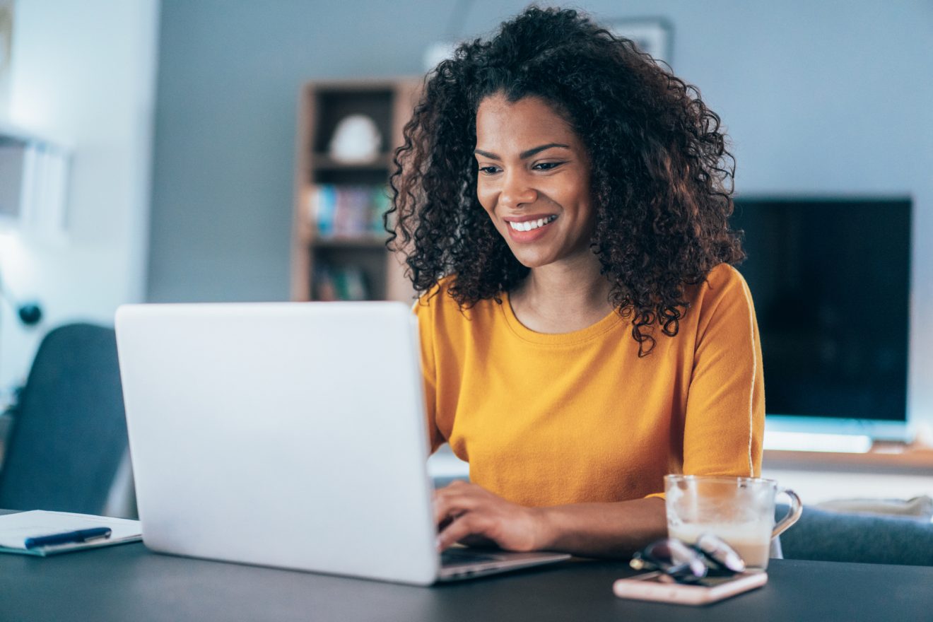 A woman smiles at her computer as she works.