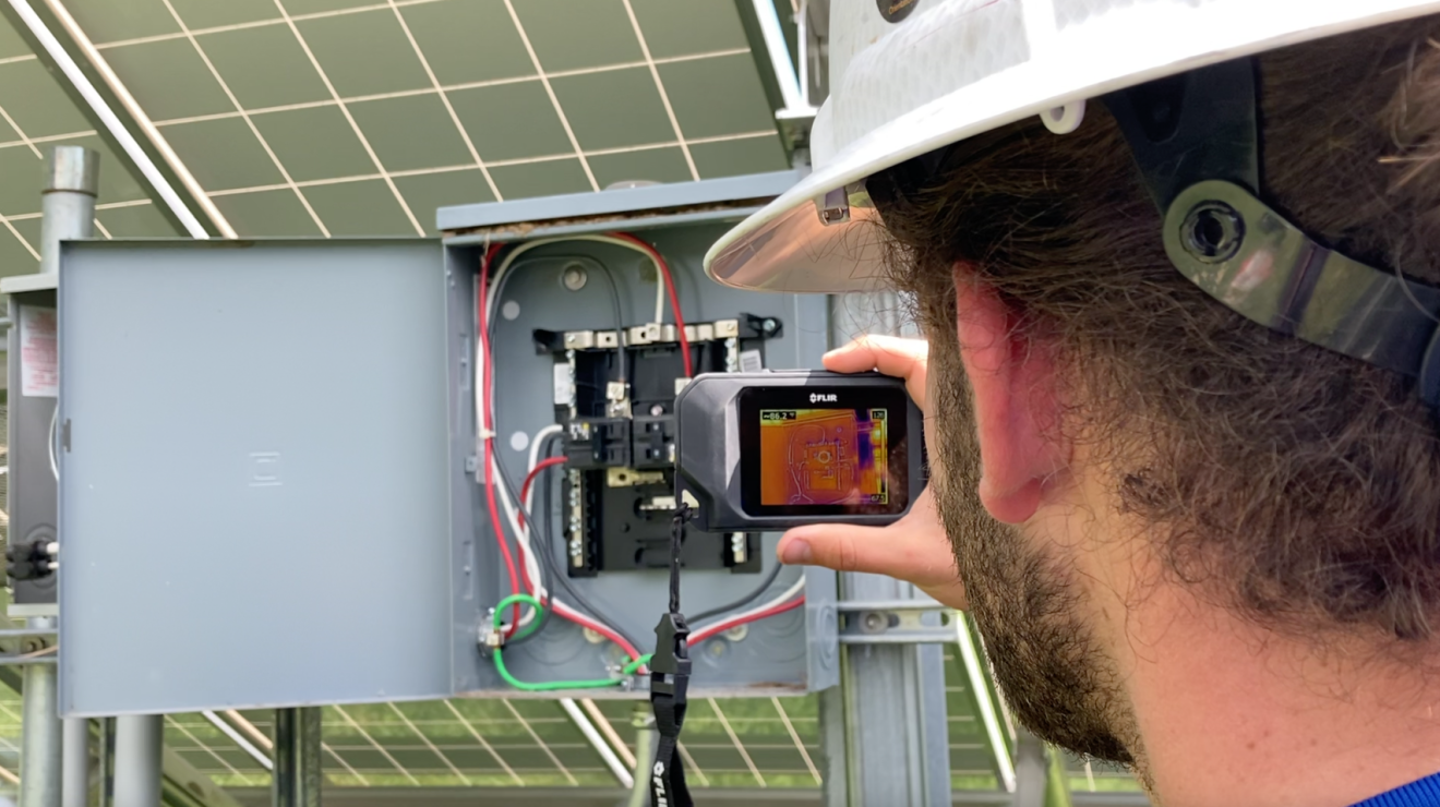 A worker taking a photo of a solar control panel box.