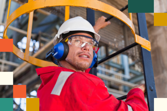 man wearing hard hat, reflective clothing, safety googles, and safety earmuffs climbing a ladder